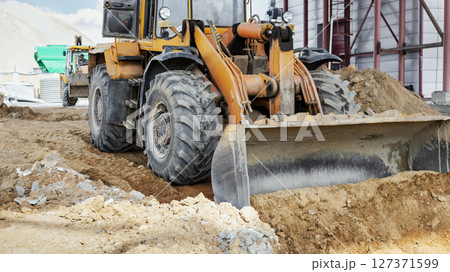 A powerful front loader on the construction site performs sanding. Moving soil with construction equipment. Excavation. A powerful front loader on the construction site performs sanding. Moving soil with construction equipment. Excavation. 127371599