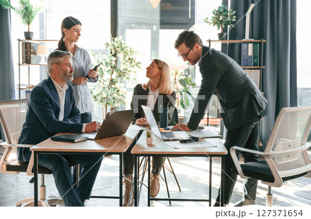 Busy workers are by the table. Group of business people are in the modern office Busy workers are by the table. Group of business people are in the modern office 127371654