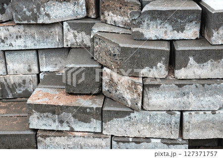 Stacked grey bricks with a textured surface displayed in construction setting during daylight hours 127371757