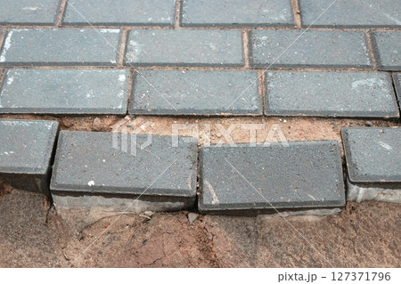 Broken pavement stones revealing soil beneath during mid-morning in an urban setting Broken pavement stones revealing soil beneath during mid-morning in an urban setting 127371796