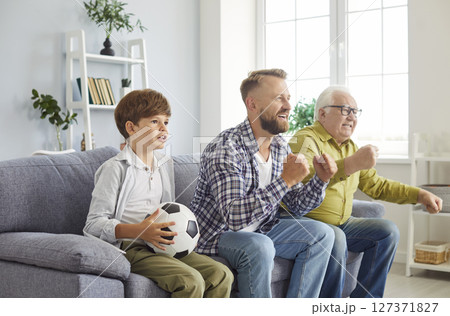 Happy family of three generation men, grandfather, father, son watching sport soccer moment on TV  127371827