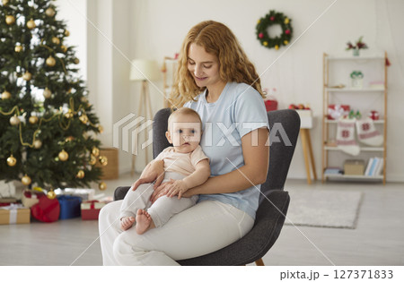 Happy young mother and her adorable little baby spending Christmas holidays at home 127371833