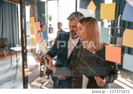 Conception of plan. Many stickers are on the glass. Group of business people are working in the modern office 127371872