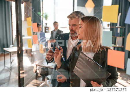 Conception of plan. Many stickers are on the glass. Group of business people are working in the modern office 127371873