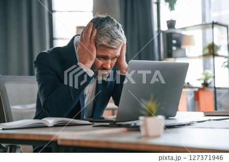 Feeling bad, tired, having headache, stressful. Senior businessman is working in the office Feeling bad, tired, having headache, stressful. Senior businessman is working in the office 127371946