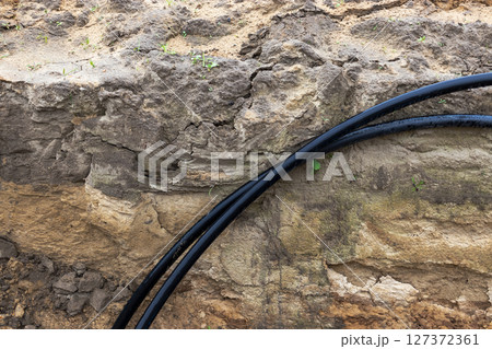 The high voltage electrical cable is laid in a trench under existing engineering sewerage networks. Laying a high voltage cable for supplying buildings with electricity. The high voltage electrical cable is laid in a trench under existing engineering sewerage networks. Laying a high voltage cable for supplying buildings with electricity. 127372361