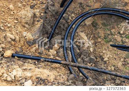 The high voltage electrical cable is laid in a trench under existing engineering sewerage networks. Laying a high voltage cable for supplying buildings with electricity. 127372363