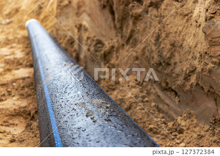 Water pipes for drinking water supply lie on the construction site. Preparation for earthworks for laying an underground pipeline. Modern water supply systems for a residential city. 127372384