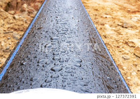 Water pipes for drinking water supply lie on the construction site. Preparation for earthworks for laying an underground pipeline. Modern water supply systems for a residential city. Water pipes for drinking water supply lie on the construction site. Preparation for earthworks for laying an underground pipeline. Modern water supply systems for a residential city. 127372391