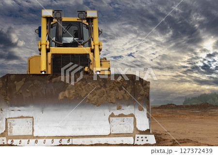 Bulldozer machine is leveling construction site. Earthmover with tractor is moving earth. Close-up. Construction heavy machinery. Bulldozer machine is leveling construction site. Earthmover with tractor is moving earth. Close-up. Construction heavy machinery. 127372439