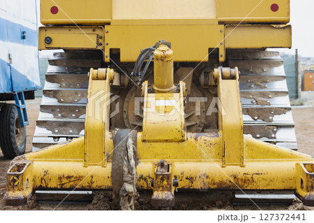 Bulldozer machine is leveling construction site. Earthmover with tractor is moving earth. Close-up. Construction heavy machinery. Bulldozer machine is leveling construction site. Earthmover with tractor is moving earth. Close-up. Construction heavy machinery. 127372441