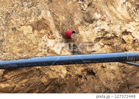 The high voltage electrical cable is laid in a trench under existing engineering sewerage networks. Laying a high voltage cable for supplying buildings with electricity. The high voltage electrical cable is laid in a trench under existing engineering sewerage networks. Laying a high voltage cable for supplying buildings with electricity. 127372448