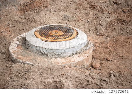 New manhole cover installation in a construction site on a sunny day 127372641