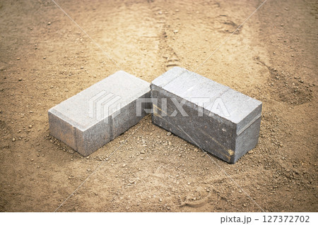 Building materials on construction site showcasing concrete blocks resting on sandy ground 127372702
