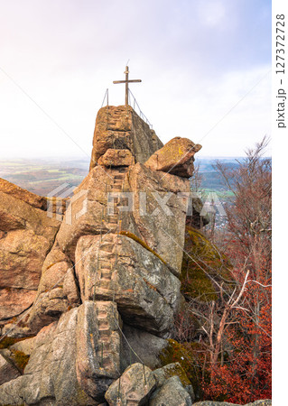 The Oresnik granite rock formation glows at sunset, showcasing a lookout point adorned with a wooden summit cross. The serene beauty of the Jizera Mountains captivates visitors. The Oresnik granite rock formation glows at sunset, showcasing a lookout point adorned with a wooden summit cross. The serene beauty of the Jizera Mountains captivates visitors. 127372728