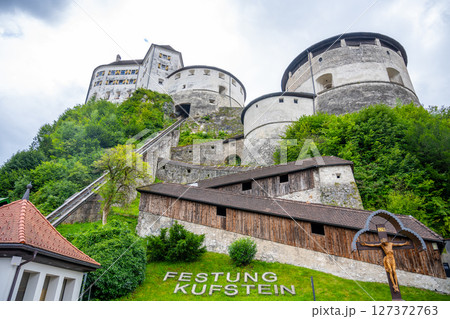 Kufstein Fortress stands majestically in Tyrol, Austria, surrounded by lush greenery. Visitors can explore its old architecture and enjoy stunning views of the surrounding mountains. 127372763
