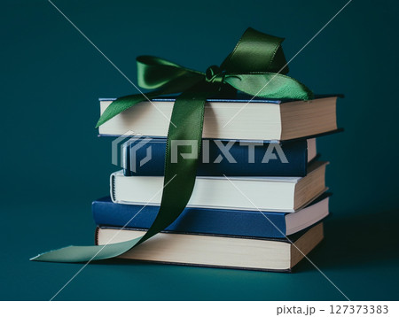 A stack of old books with worn covers and aged pages, featuring a green ribbon bookmark. 127373383
