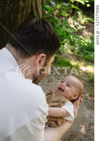 Father Holding Baby in Sunny Park 127373666