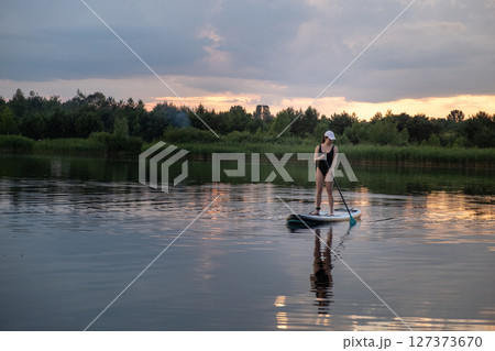 Paddleboarding at Sunset on a Tranquil Lake 127373670