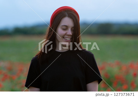 Young Woman in Poppy Field with Red Hat 127373671