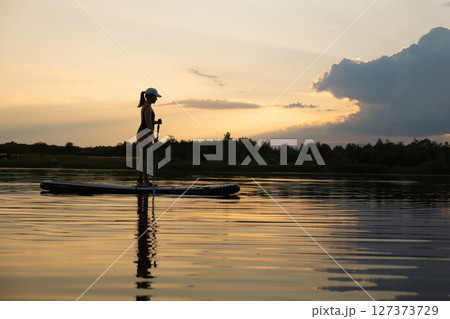 Paddleboarding at Sunset on a Tranquil Lake 127373729