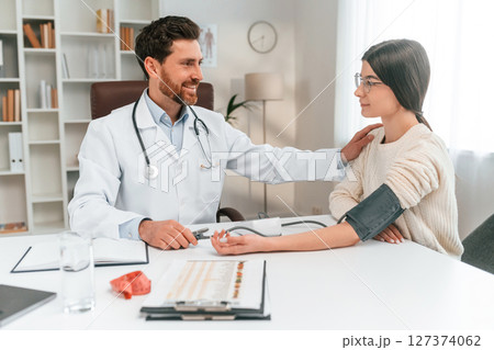 Blood pressure measurement. With woman. Doctor in formal clothes is working in the cabinet 127374062