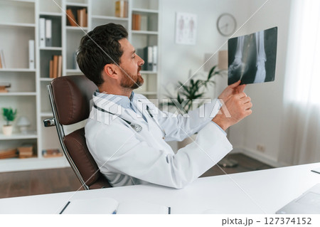 Looking at x-ray. Doctor in formal clothes is working in the cabinet Looking at x-ray. Doctor in formal clothes is working in the cabinet 127374152