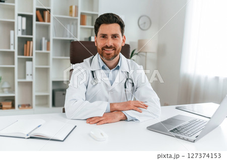 Sitting by a table. Doctor in formal clothes is working in the cabinet Sitting by a table. Doctor in formal clothes is working in the cabinet 127374153