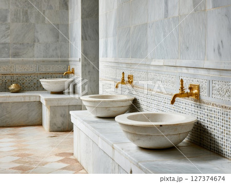 Elegant marble hammam interior featuring ornate basins and golden faucets in serene atmosphere 127374674