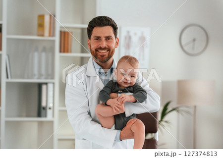 Holding boy in hands. Doctor with little baby is working in the cabinet 127374813