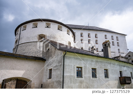 Visitors appreciate the historical architecture of Kufstein Fortress in Tyrol, Austria. The stronghold's white stone walls stand out against the cloudy sky, inviting exploration and discovery. 127375529