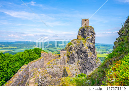 Visitors admire the stunning views from Panna Tower, situated atop a rocky cliff at Trosky Castle Ruins. The lush green landscapes of Bohemian Paradise stretch far and wide. 127375549