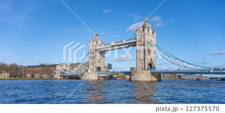 Tower Bridge stands majestically over the River Thames, showcasing its iconic structure against a clear blue sky. Visitors can admire the beauty of London from this historic landmark. 127375570