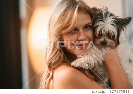 Embracing the animal. Beautiful young woman is with little dog indoors Embracing the animal. Beautiful young woman is with little dog indoors 127375911