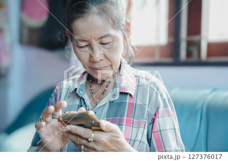 An elderly woman using a smartphone while sitting comfortably at home, showcasing modern technology in daily life. An elderly woman using a smartphone while sitting comfortably at home, showcasing modern technology in daily life. 127376017