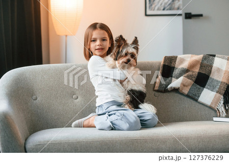 Little girl is at home with cute dog on the sofa 127376229