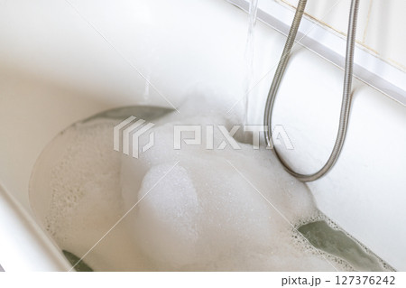 taking water with foam into the bath, spa, relaxation taking water with foam into the bath, spa, relaxation 127376242