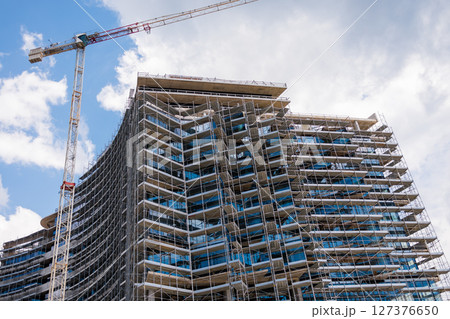 Construction site with tower crane against the sky. Concept of modern architecture, civil engineering, and urban development. 127376650