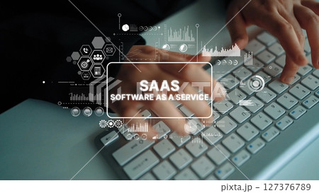 Hands Typing on Keyboard with Graphics Representing SaaS Concepts and Digital Technology in Office Environment. Asymptotic smart data analytic 127376789