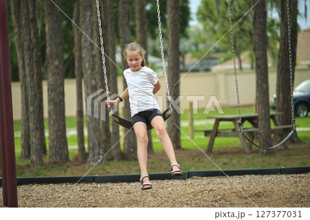 Young pretty excited teenage girl jumping out of the swings on summer vacations sunny day. Danger of accident concept 127377031