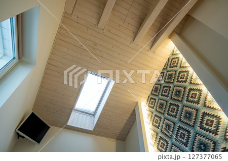 Wooden ceiling in a contemporary mansard room with attic window ob decorative planks surface. Wooden ceiling in a contemporary mansard room with attic window ob decorative planks surface. 127377065