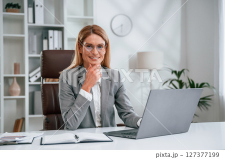Using laptop. Woman in business formal clothes is working in office Using laptop. Woman in business formal clothes is working in office 127377199