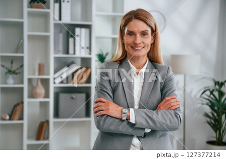 Standing with arms crossed. Woman in business formal clothes is working in office 127377214
