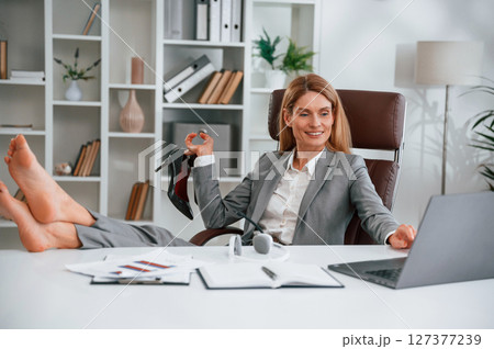 Sitting with legs on the table. Woman in business formal clothes is working in office Sitting with legs on the table. Woman in business formal clothes is working in office 127377239