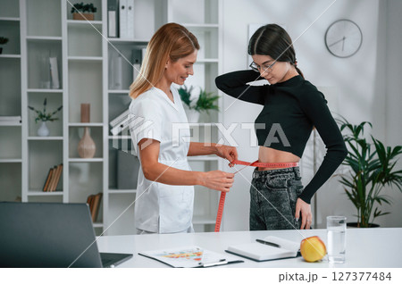 Conception of diet, gain weight, measuring the waist. Young woman at a nutritionist's appointment. Medical care Conception of diet, gain weight, measuring the waist. Young woman at a nutritionist's appointment. Medical care 127377484