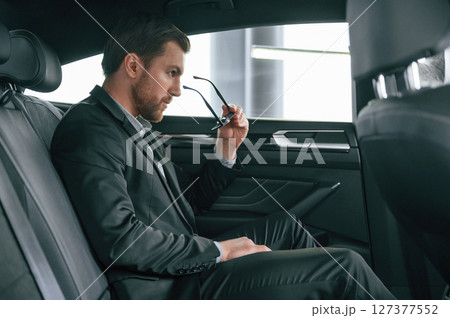 In comfortable modern automobile. Man in formal business clothes In comfortable modern automobile. Man in formal business clothes 127377552