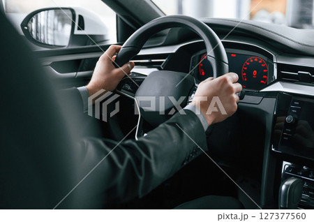 Driving the car. Man in formal business clothes is sitting in the modern automobile 127377560