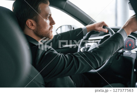 Driving the car. Man in formal business clothes is sitting in the modern automobile Driving the car. Man in formal business clothes is sitting in the modern automobile 127377563