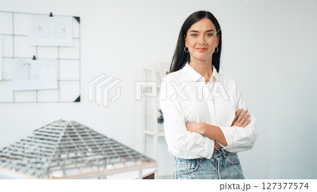 Young beautiful architect poses confidently with house model. Immaculate. Young beautiful architect poses confidently with house model. Immaculate. 127377574
