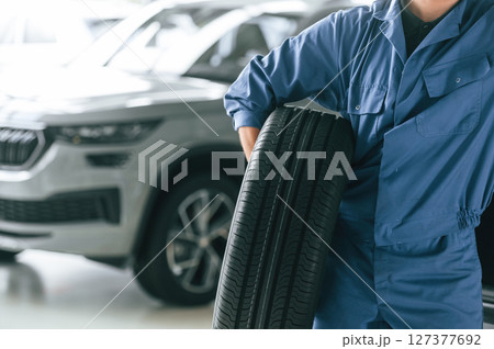 Tire replacement concept. Man in blue uniform is working in the car service 127377692